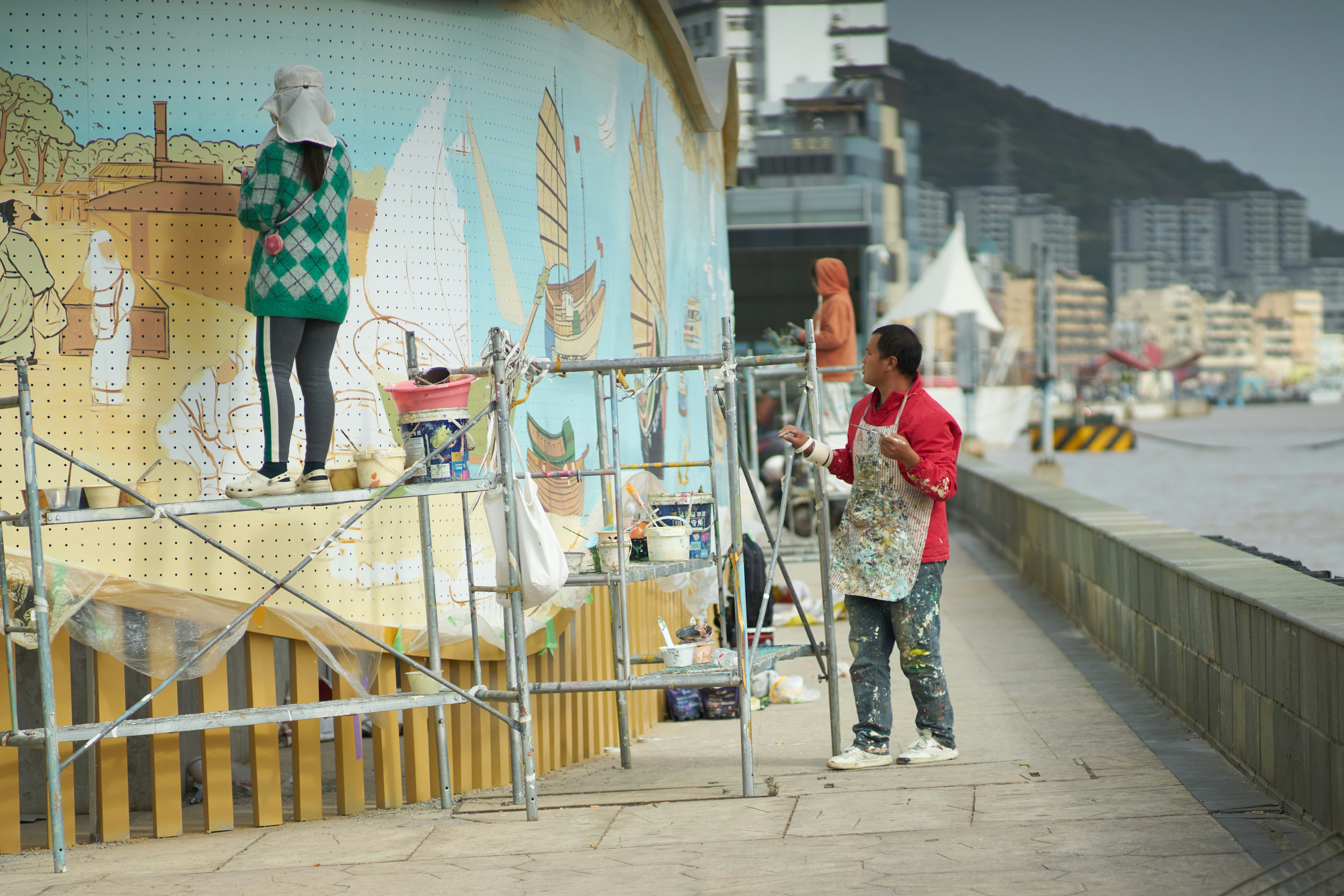 Deux personnes peignant ensemble une fresque sur un mur d'espace public